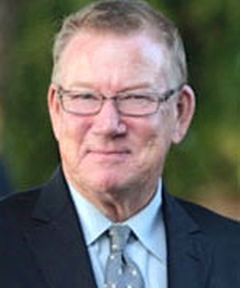 Smiling-man-in-dark-blue-suit-with-light-blue-shirt-wearing-glasses